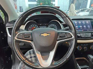 Руль с эмблемой Chevrolet и часть передней панели: кнопки управления на руле, хорошо читаемые шкалы спидометра и тахометра.