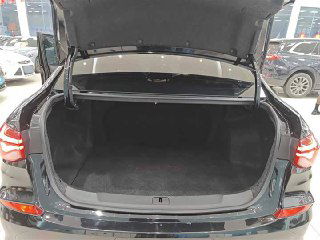 Открытый багажник Chevrolet Monza: глубокий грузовой отсек, чистая обшивка багажника и вид на задний бампер в выставочном зале.