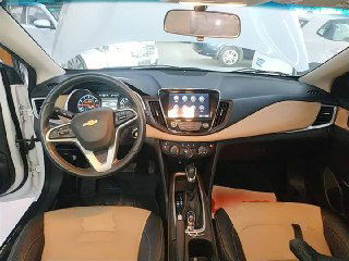 Вид торпедо и рулевого колеса Chevrolet Monza 2022: центральная консоль с мультимедийным экраном и панелью приборов, салон в бежево-чёрной отделке.