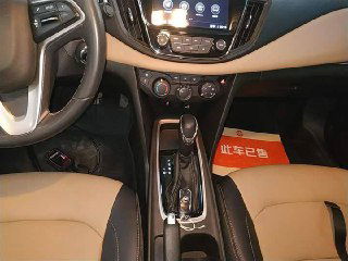 Крупный план селектора АКПП и декоративных вставок рядом с передним подлокотником в салоне Chevrolet Monza 2022, видно отделку и кнопки управления.