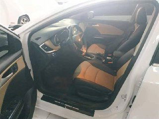 Интерьер Chevrolet Monza 2022, общий вид передней части салона с открытой дверью: руль, сиденья и консоль в торговом зале автосалона.