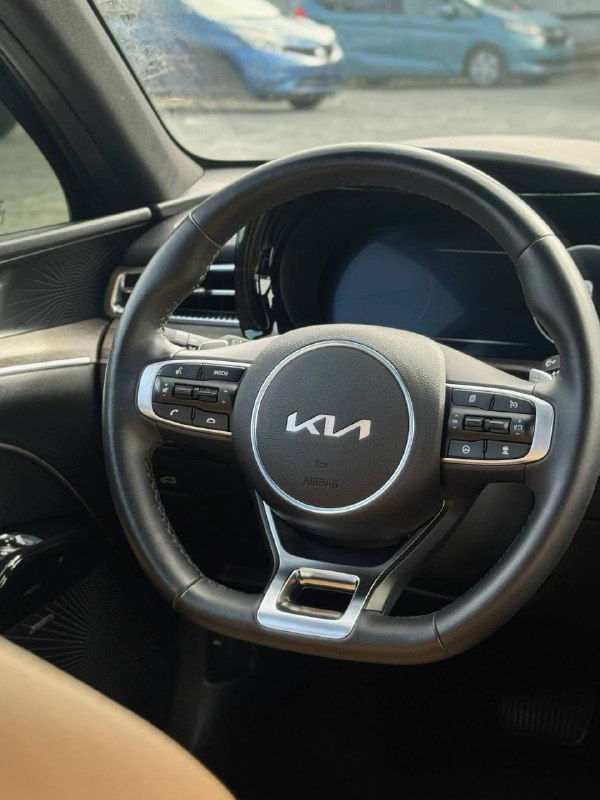Руль KIA с фирменным логотипом на центральной накладке — интерьерный крупный план с видимыми органами управления и кнопками мультируля.