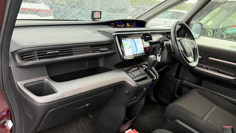 Интерьер Honda Stepwgn 2019: передняя панель, сенсорный экран медиасистемы, центральная консоль и передние сиденья — состояние салона видно на фото.