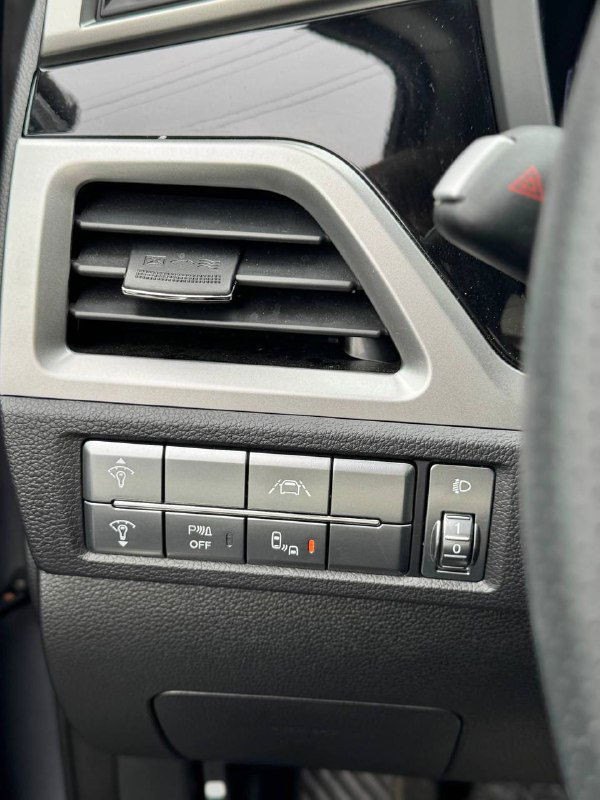 Крупный план боковой панели и набора кнопок у рулевого колеса SsangYong Korando — системы помощи, вентиляционная решётка и регулировки.