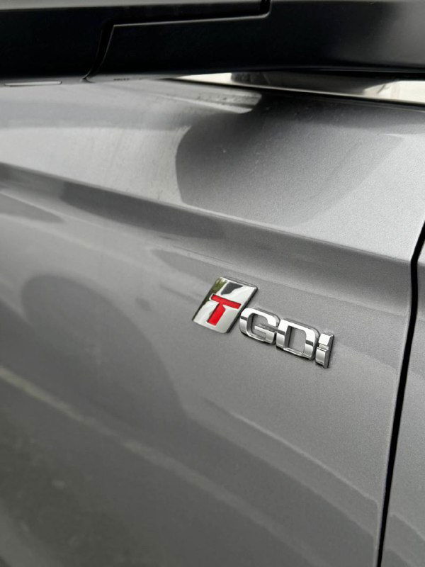 Ближний план шильдика двигателя на крыле серого SsangYong Korando с маркировкой 1.6DI — акцент на обозначении силового агрегата.