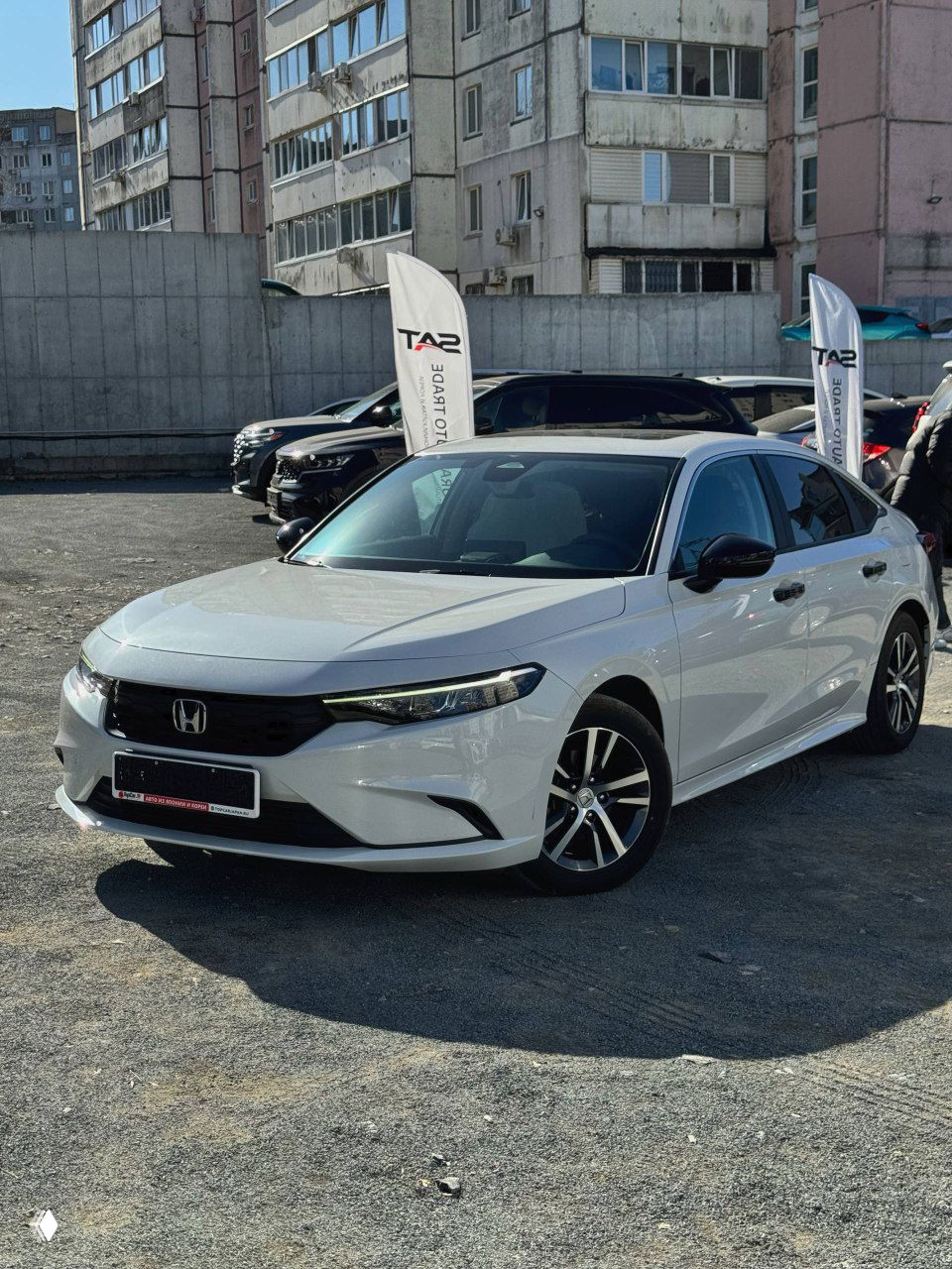 Белая Honda Integra 2022 припаркована на открытой стоянке при ярком дневном освещении; вид спереди-углом, чистый кузов и колеса.