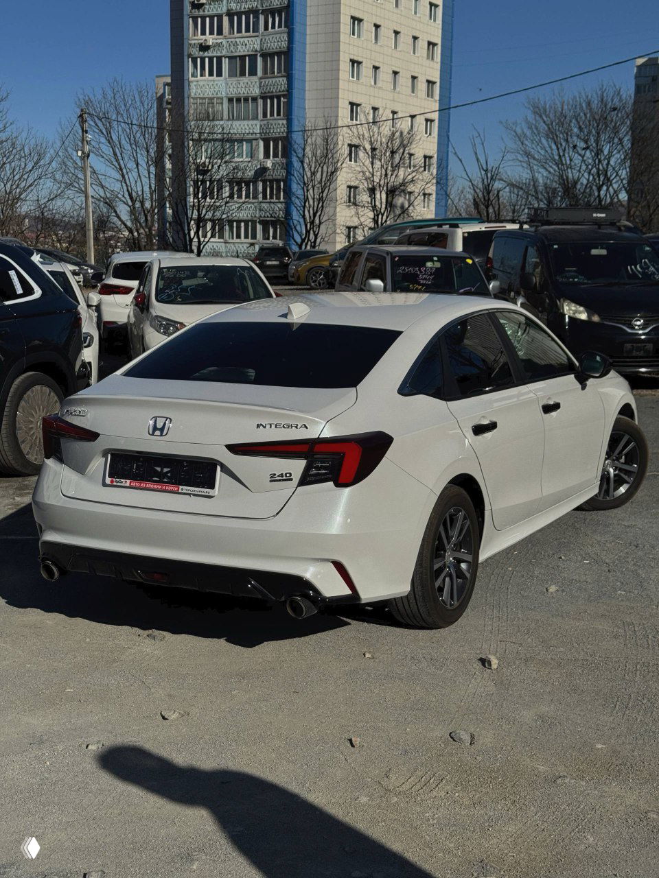 Задняя часть белой Honda Integra 2022 на стоянке; видно название модели на крышке багажника и хромированные патрубки выхлопа.