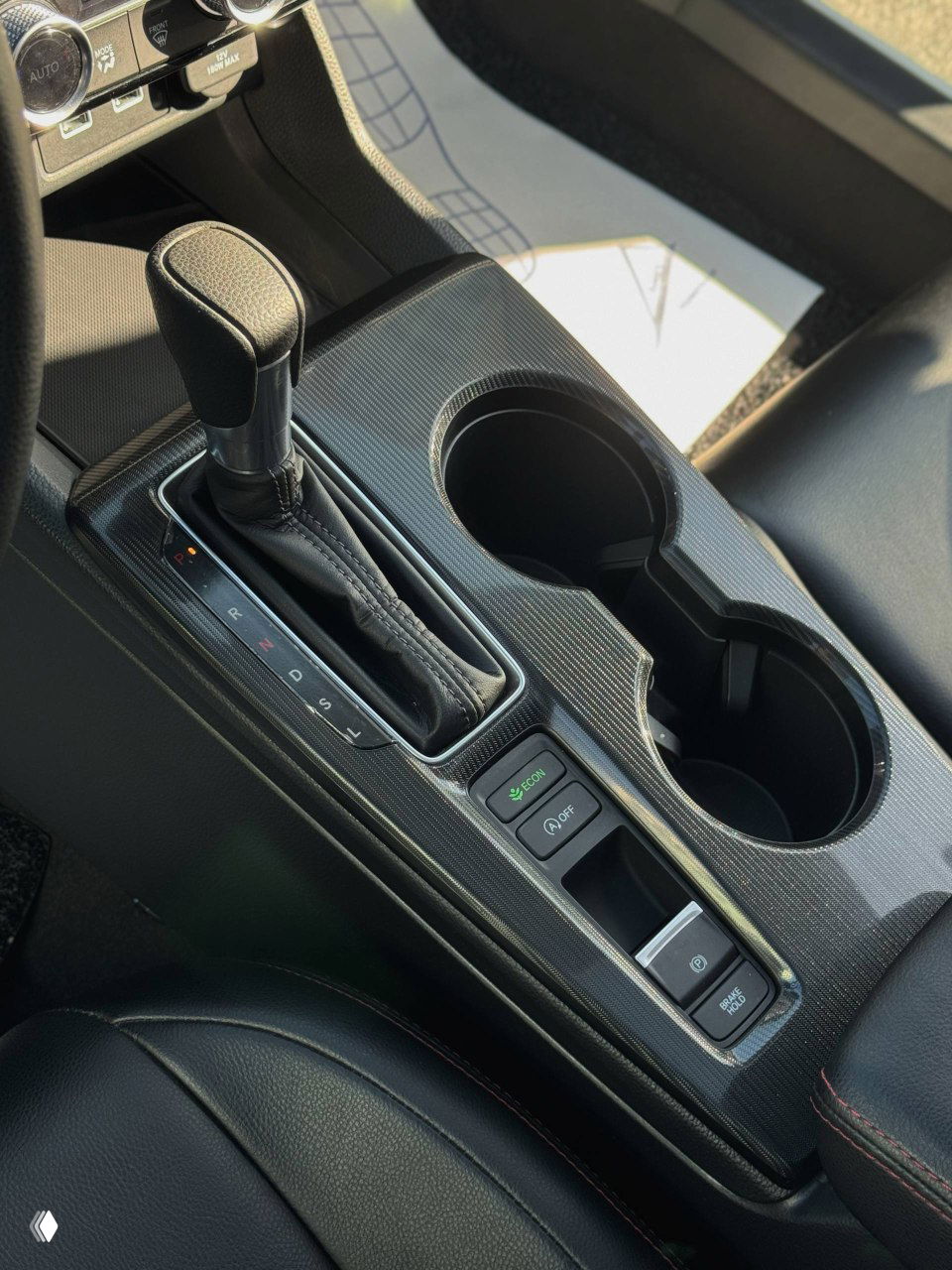 Ближний план центрального туннеля Honda Integra: селектор вариатора, боксы для напитков и кнопки электронных систем в зоне между сиденьями.