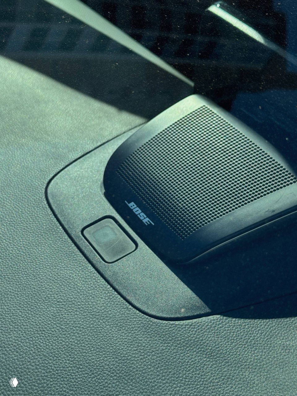 Крупный план акустической решётки с логотипом Bose на торпедо Honda Integra; видно текстуру панели и отражение солнца на стекле.