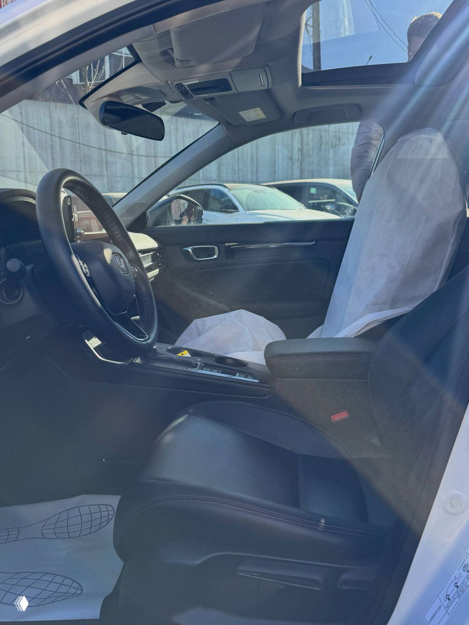 Фотография салона Honda Integra с раскрытым панорамным люком и защитными чехлами на сиденьях; видно переднее пассажирское место.