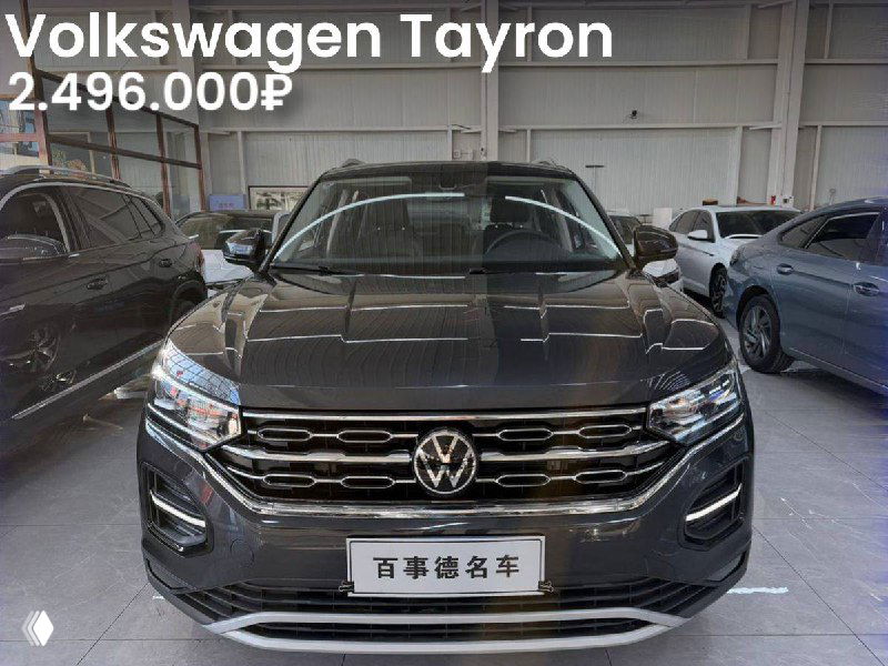Фронтальный вид Volkswagen Tayron в выставочном зале: автомобиль чёрного цвета с заметной эмблемой VW и табличкой с информацией на китайском.