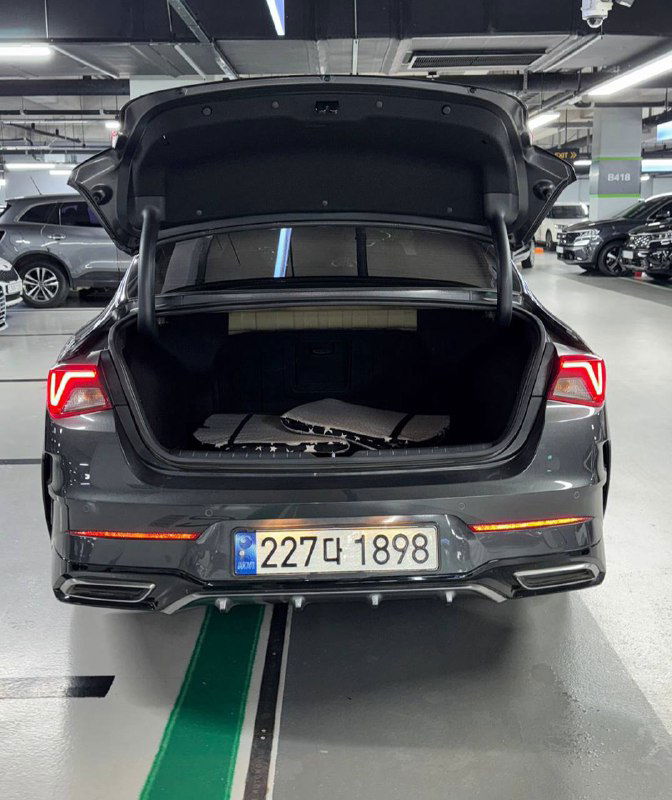 Открытый багажник и задний бампер KIA K5 2023 с видимым корейским номером; фотография для демонстрации объёма багажника и состояния задней части автомобиля