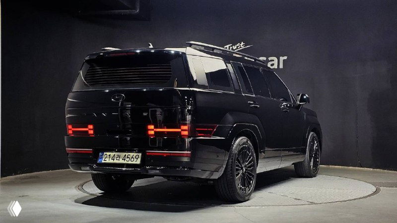 Hyundai Santa Fe 2024 — вид сзади на вращающейся выставочной площадке: прозрачные фонари, багажная дверь и задний бампер в крупном плане.