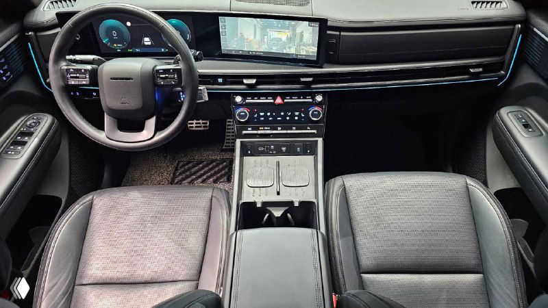 Салон Hyundai Santa Fe 2024 Calligraphy: панорамный вид на приборную панель, широкую мультимедийную панель и центральный тоннель с подстаканниками.