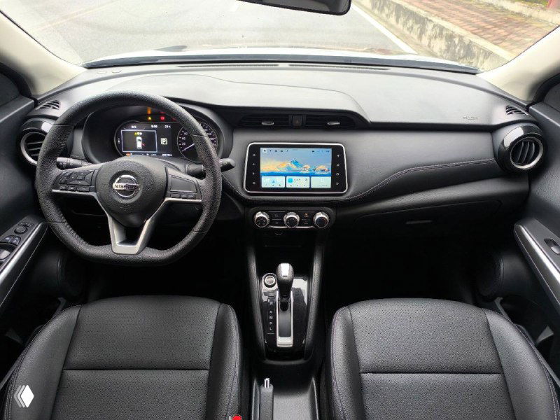 Салон Nissan Kicks 2021: торпедо, рулевое колесо и мультимедиа-экран — интерьер с передними креслами и центральной консолью.