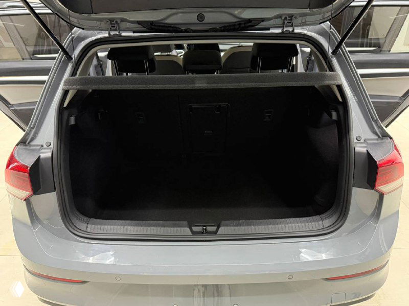 Открытый багажник Volkswagen Golf 2021: вид из задней части на вместительную нишу багажного отделения и порог погрузки в шоурумных условиях.