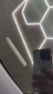 Ещё один снимок VIN на лобовом стекле Volkswagen Golf 2021 с яркими отражениями потолочных ламп и частичным отображением салона на заднем плане.