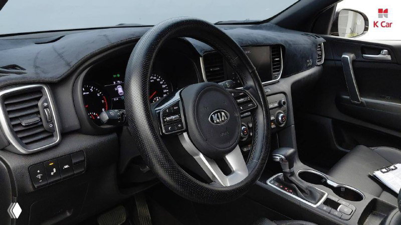 Интерьер: руль и приборная панель KIA Sportage Prestige 2021, вид на спидометр, мультифункциональный руль и центральные регуляторы.