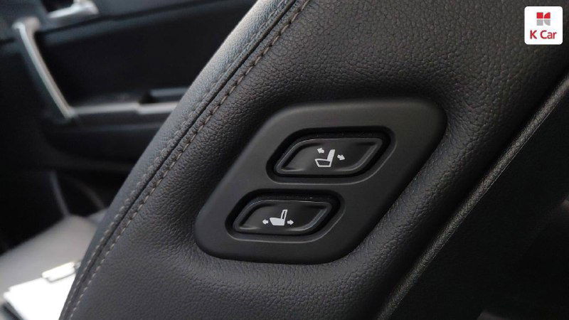 Крупный план кнопок регулировки сидений на боковой панели переднего кресла KIA Sportage, вид на электрические регуляторы и их маркировку.