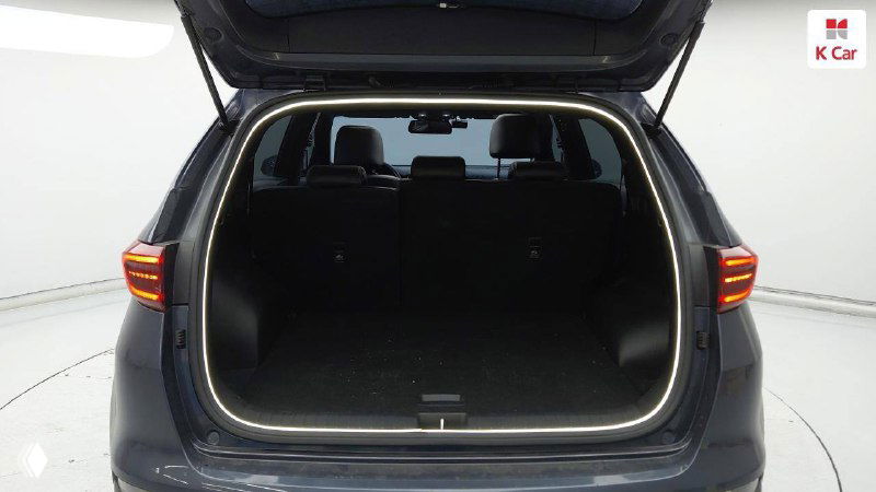 Открытый багажник KIA Sportage 2021: ровный пол грузового отделения, вид зала осмотра и состояние пространства для поклажи на фоне павильона.