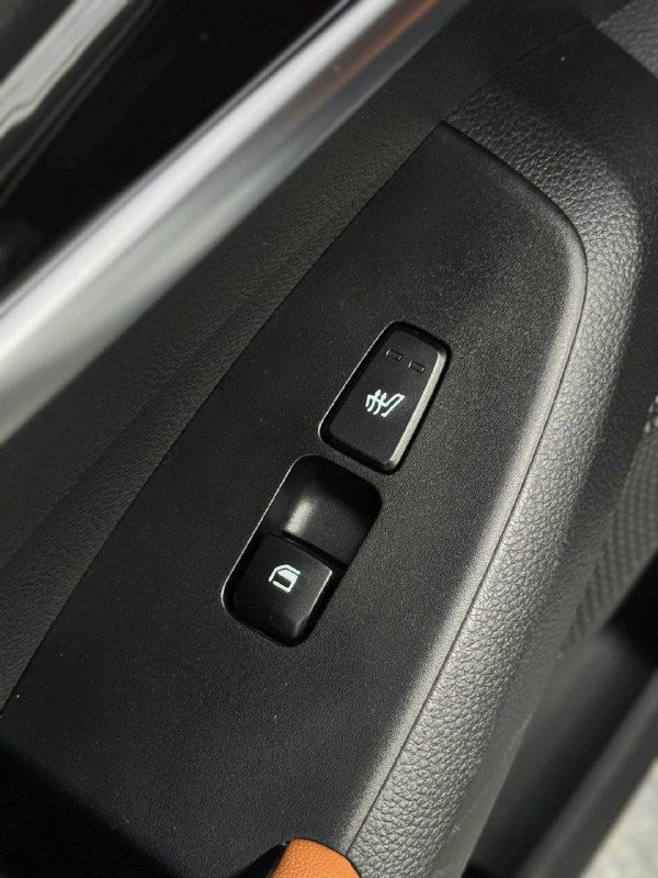 Кнопки управления стеклоподъёмниками и подогрева на дверной панели KIA Seltos — крупный план элементов управления.