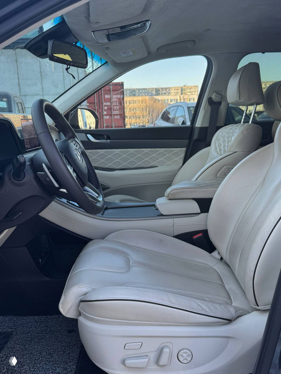 Промежуточный вид передних сидений и пространства салона Hyundai Palisade: светлая кожаная обивка, регулировки и панорамный обзор.