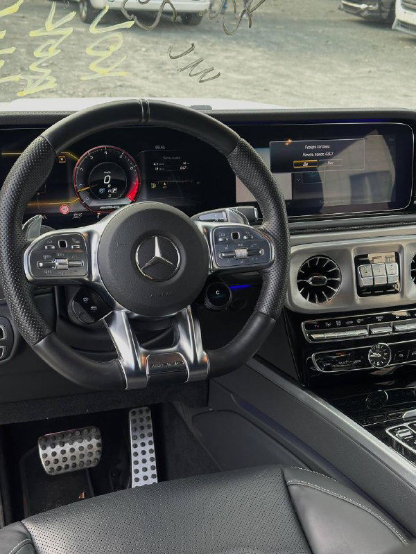 Интерьер: руль Mercedes G63 AMG, цифровая приборная панель и экран мультимедиа, видна отделка и кнопки управления на руле.
