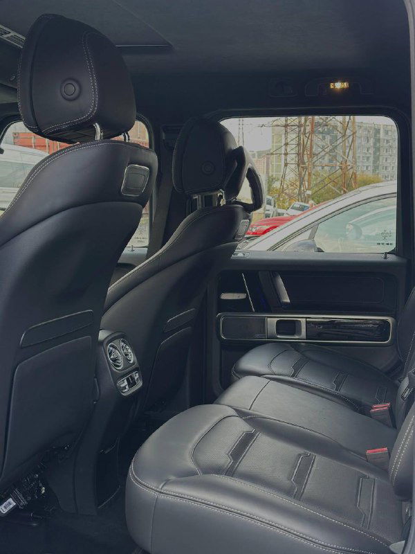 Задние кожаные сиденья Mercedes G63 AMG в пассжирской части, видна отделка дверей и пространство для пассажиров с хорошим обзором.