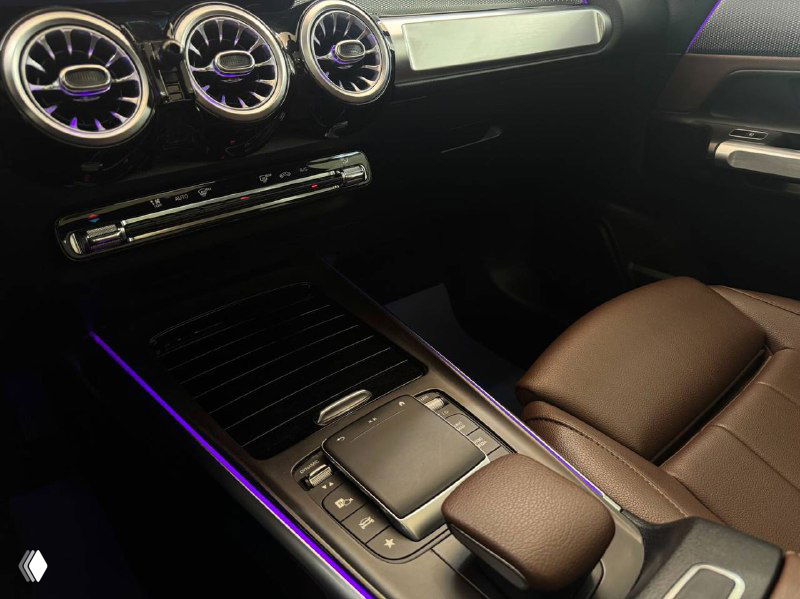 Центральная консоль Mercedes GLB с тачпадом, декоративной подсветкой и кожаной отделкой подлокотника, съемный ракурс демонстрирует качество материалов.