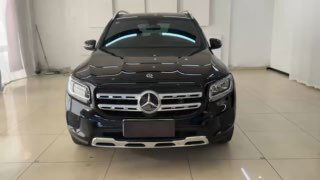 Широкий фронтальный кадр чёрного Mercedes GLB в салоне: автомобиль расположен в выставочном зале, видна передняя оптика и бампер.