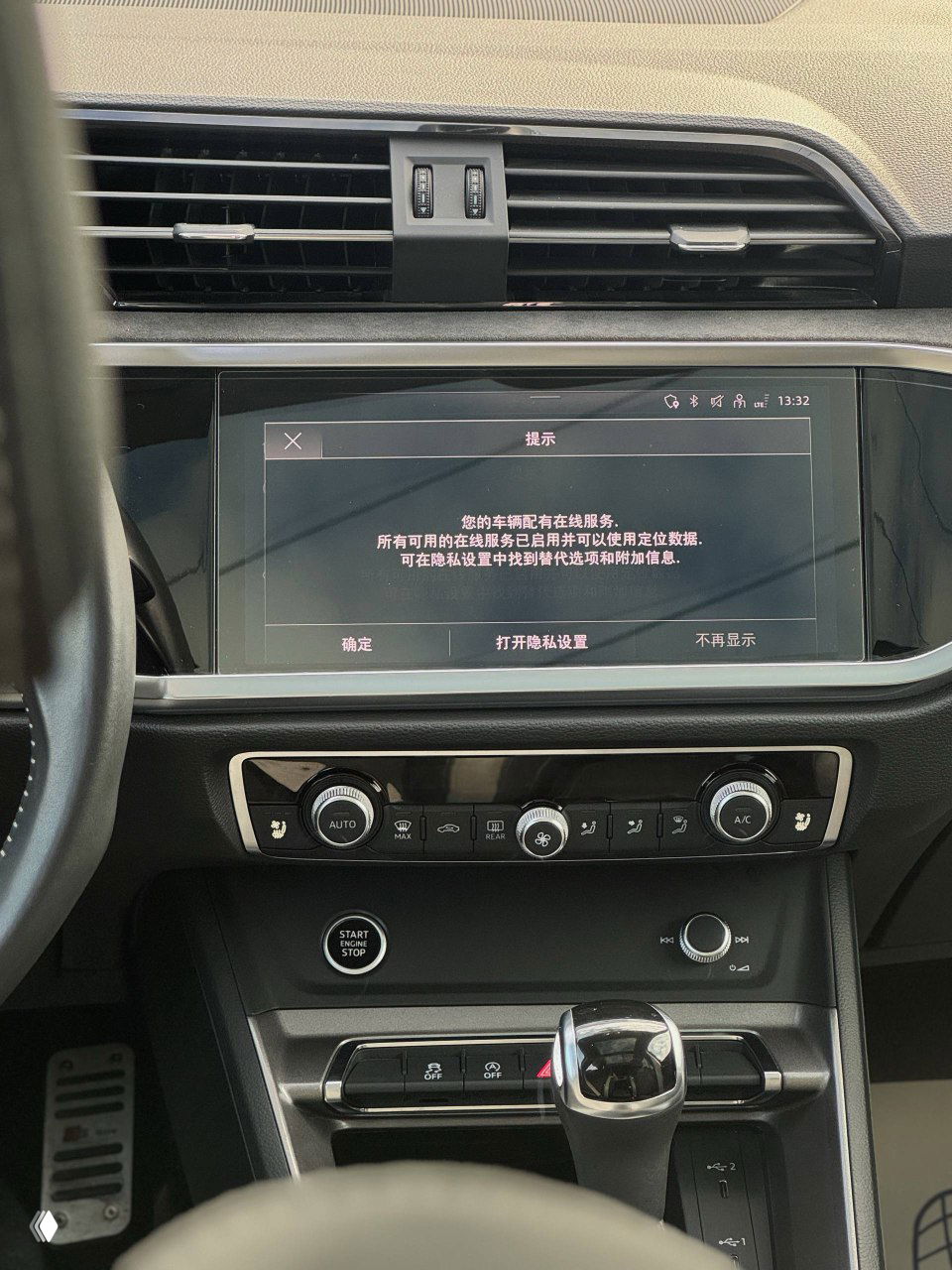 Дисплей мультимедиа Audi с отображённым сообщением на китайском языке, панель управления климатом и элементы центральной консоли.