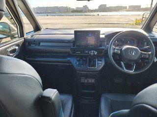 Интерьер Honda StepWGN Spada 2024: вид на центральную консоль и мультимедийный экран, правый руль, общий обзор приборной панели и салона.