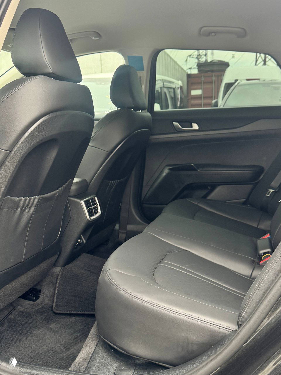 Задний ряд сидений KIA K5: кожаная обивка, пространство для ног и вентиляционные дефлекторы между передними сиденьями.