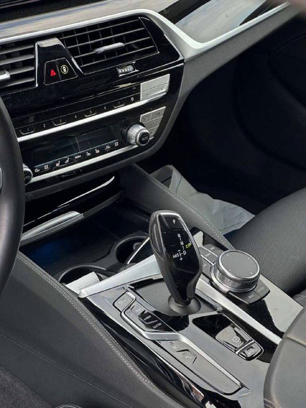 Центральная консоль BMW 530e с селектором автоматической коробки передач, шайбой управления iDrive и декоративными глянцевыми вставками интерьера.