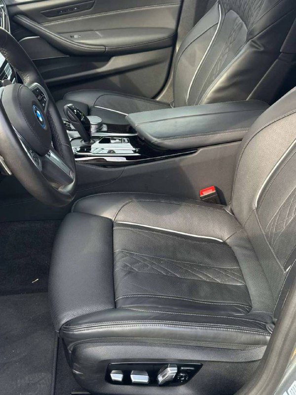 Переднее сиденье и часть водительской зоны BMW 530e — кожаная обивка, регулировки сиденья и средняя консоль с подлокотником.