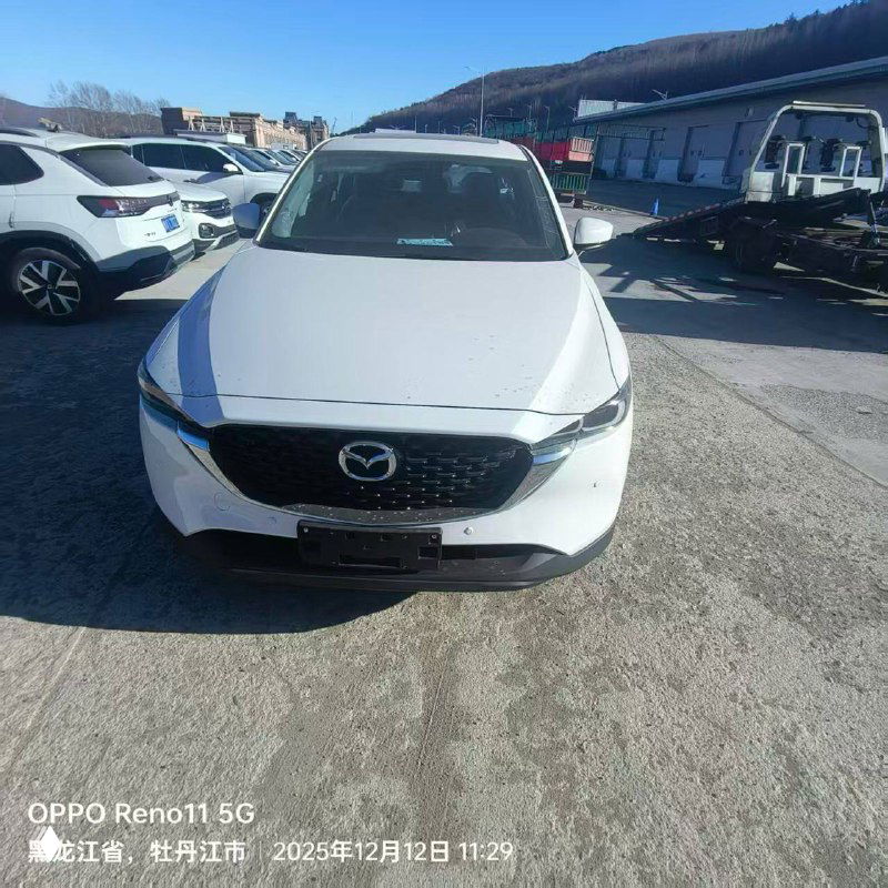 Фронтальный ракурс белой Mazda CX-5 на стоянке порта: заметны окружающие автомобили и дневное освещение, снимок для отчета клиента.