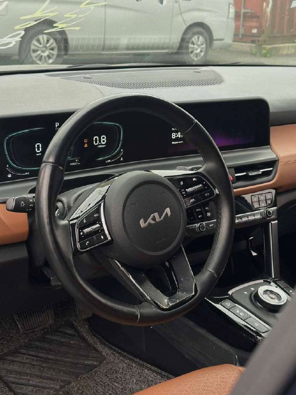 Интерьер автомобиля KIA Seltos — панель приборов и рулевое колесо с логотипом KIA, цифровая приборная панель и сенсорный экран.