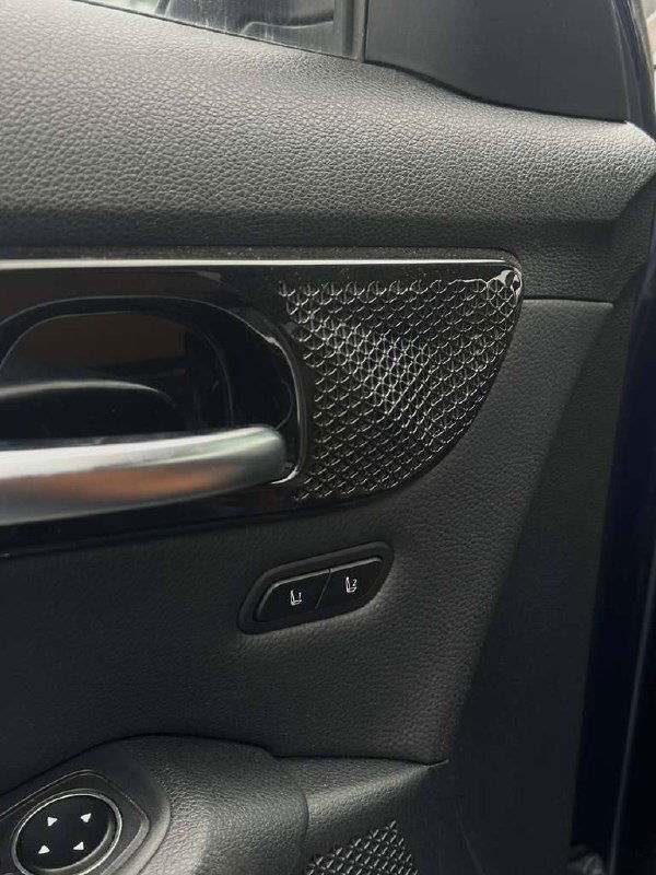 Деталь дверной обшивки KIA Seltos: декоративная вставка, ручка двери и кнопки управления памятью сиденья в крупном плане.