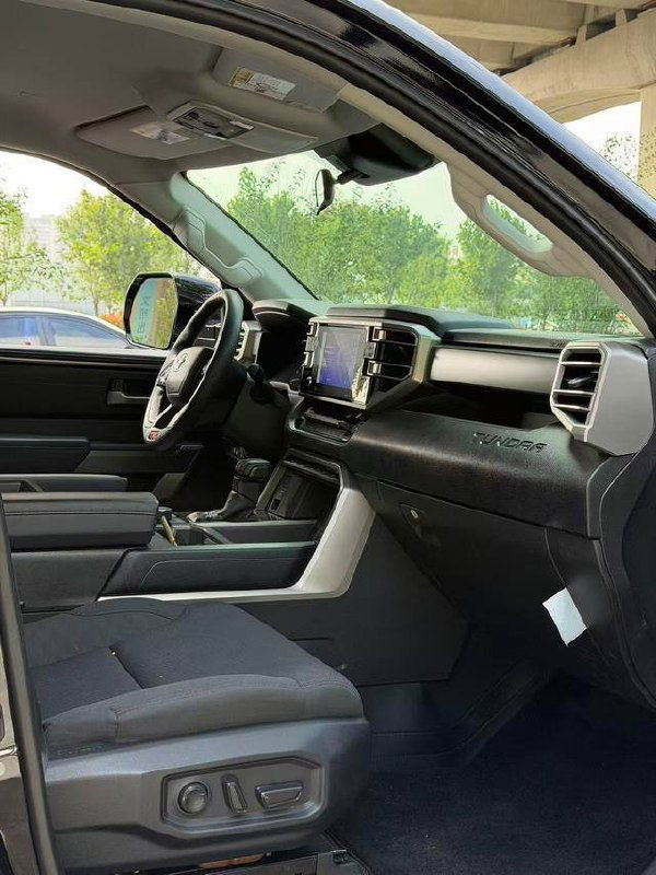 Интерьер Toyota Tundra, передняя панель и руль, крупный сенсорный экран медиасистемы и чёрная обивка салона, вид со стороны водителя.