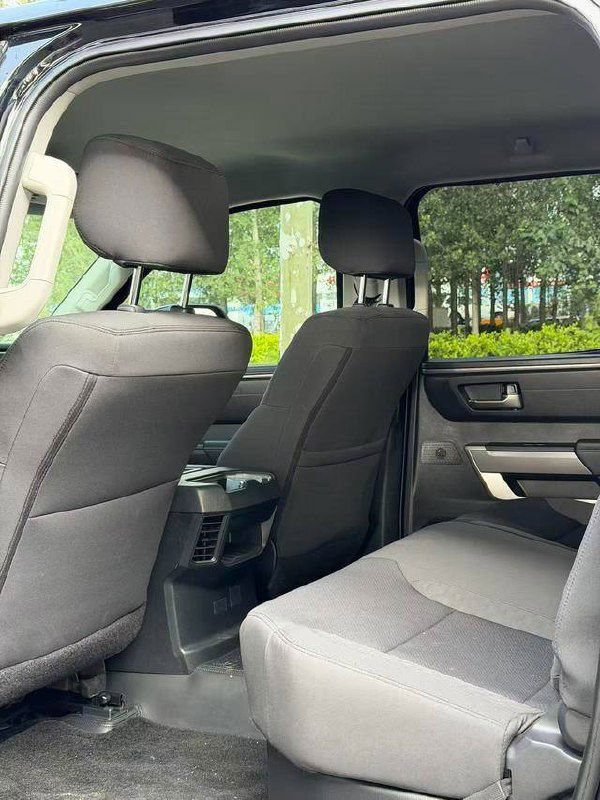 Задние сиденья Toyota Tundra с тёмной тканевой обивкой, пространство для ног и панорамный вид через боковой проём двери.
