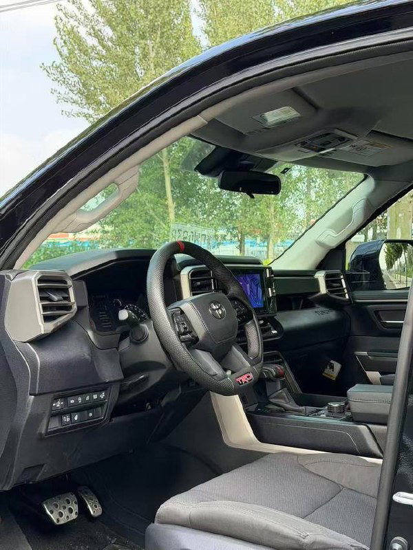 Крупный план водительского места Toyota Tundra: руль, приборная панель и центральная консоль с селектором АКПП и блоком управления.