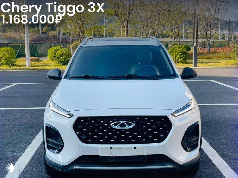 Фронтальное фото белого Chery Tiggo 3X 2022 года в стоянке; чётко видна решётка радиатора, фары и ровная асфальтовая зона вокруг.