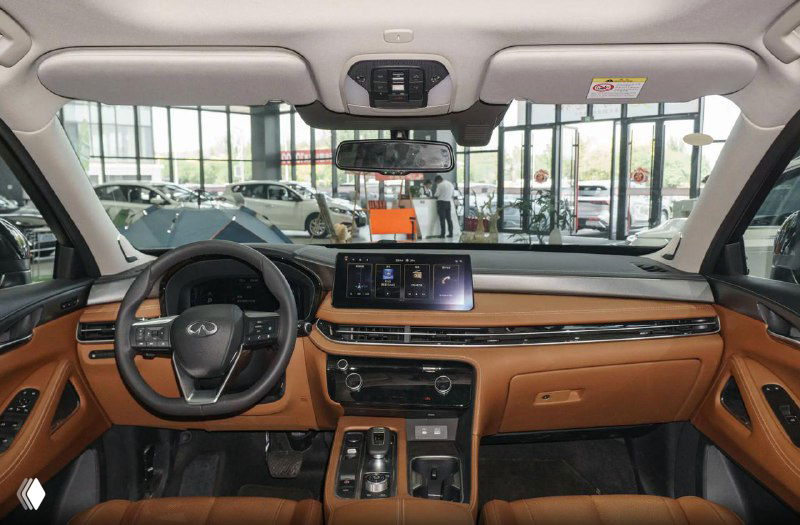 Интерьер Infiniti QX60 — панель приборов, мультимедийный экран и рукояти управления на центральной консоли, коричневая кожаная отделка.