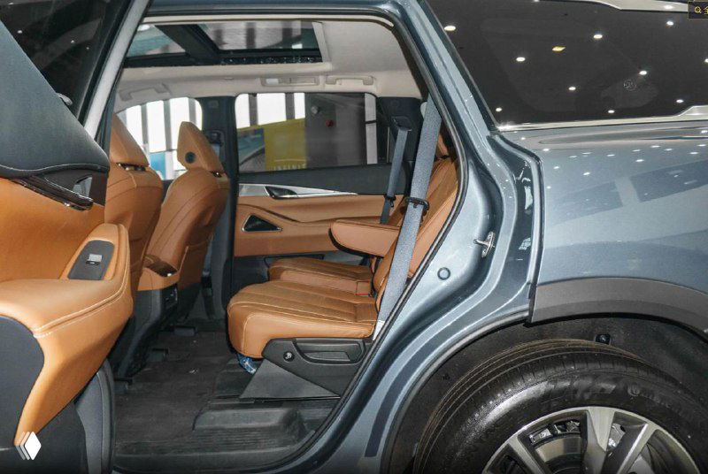 Задний ряд сидений Infiniti QX60 в коричневой коже — пространство для пассажиров, вид через открытую заднюю дверь на салон и арки колёс.
