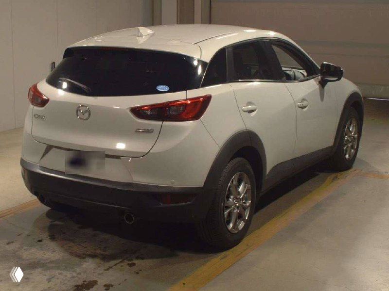 Белая Mazda CX-3 2017 года, вид сзади и с левого бока на ярде в Японии — номер скрыт, видны задняя оптика и состояние кузова.
