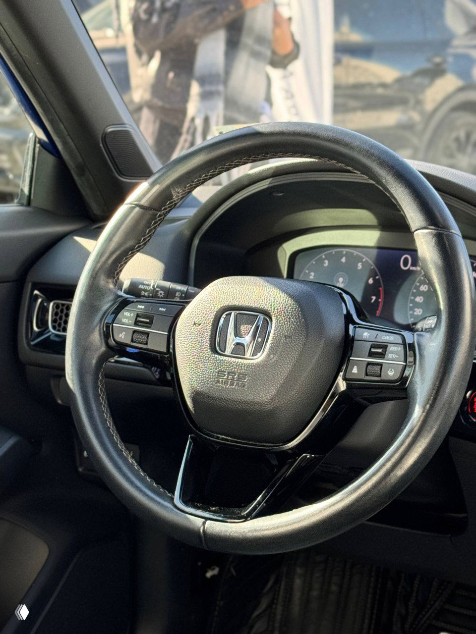 Руль и приборная панель Honda Civic 2021: кожаный руль с кнопками управления, вид на тахометр и часть приборки, состояние салона видно хорошо.