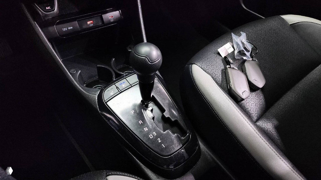 Рычаг автоматической коробки передач KIA Morning 2025 и комплект ключей, размещённые на переднем пассажирском сиденье в закрытом салоне.