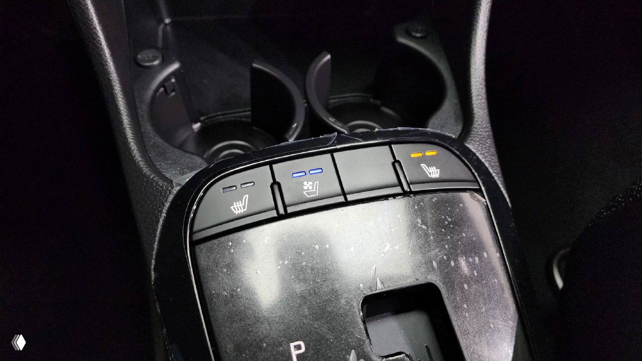 Панель с кнопками подогрева сидений и элементы центральной консоли KIA Morning 2025: индикаторы режимов и область вокруг селектора передач.