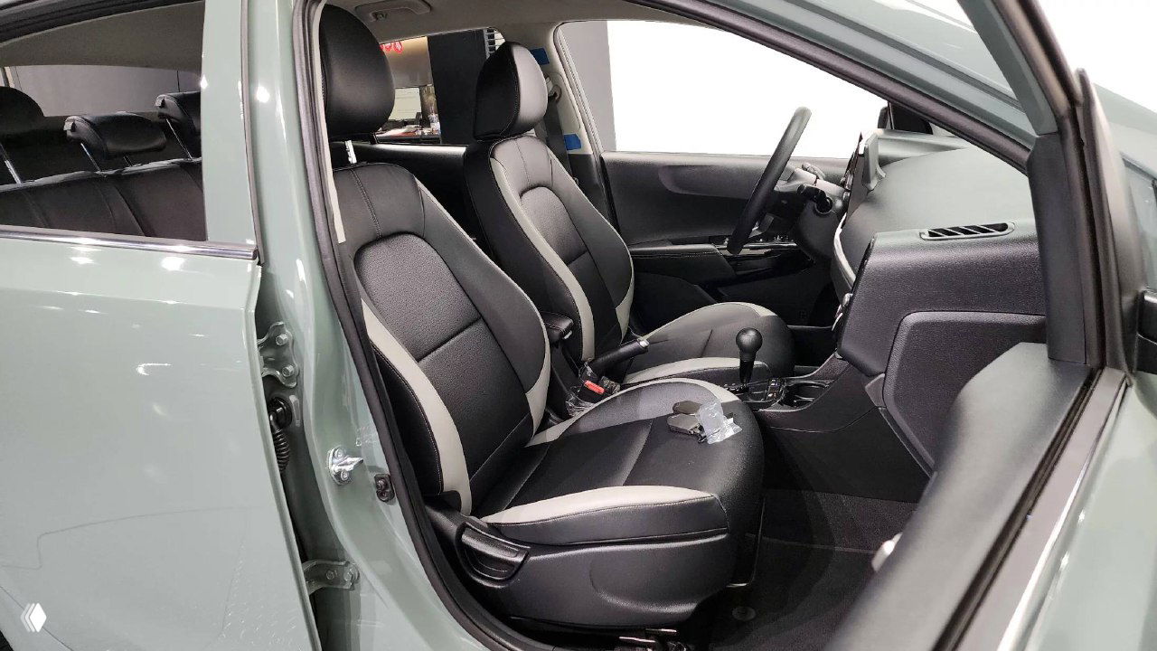 Передние сиденья KIA Morning 2025 в чёрно‑серой отделке, открыта передняя дверь, вид на пространство для водителя и посадочные места.