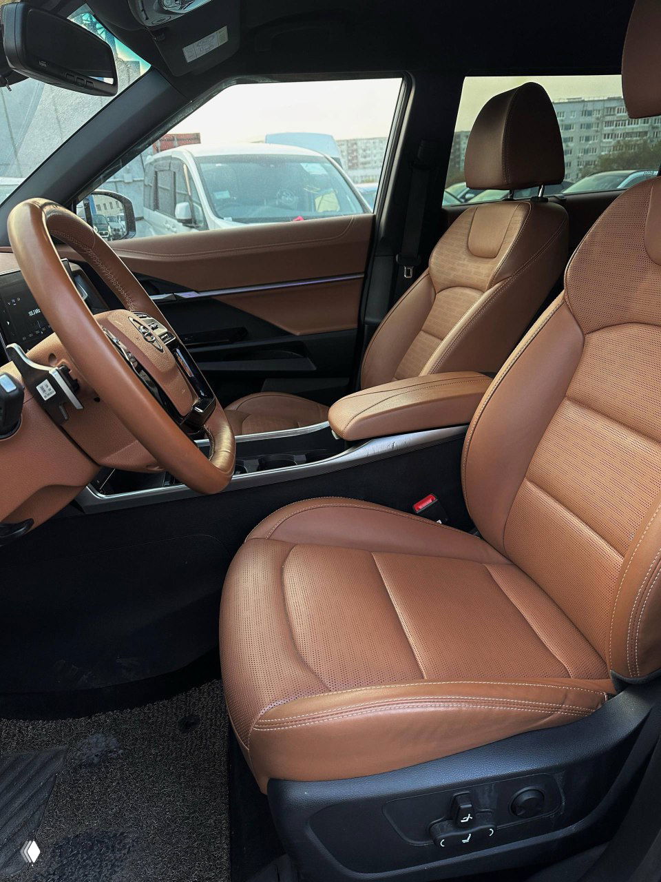 Передние сиденья SsangYong Torres в коричневой отделке, вид с пассажирской стороны на комфортные кожаные кресла и центральный туннель с подлокотником.